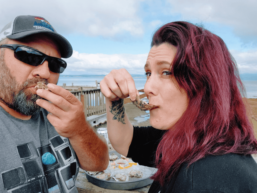 Two people eating fresh oysters outside at Oysterville Sea Farms in Oysterville, Washington.