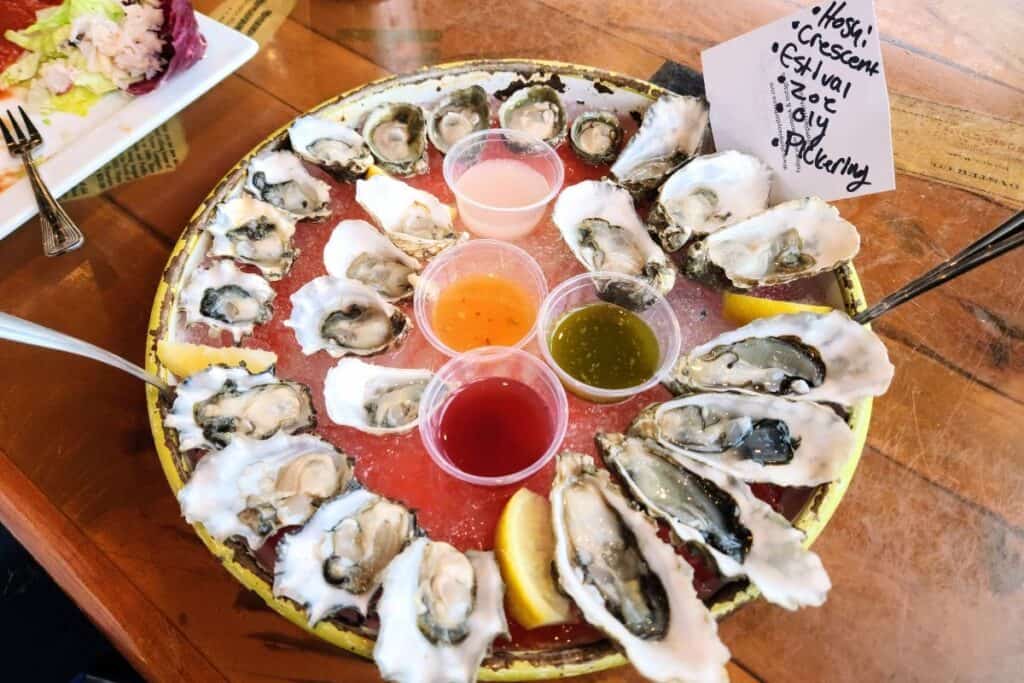 Two dozen fresh oysters in a half shell on a chilled platter with fresh sauces at the Olympia Oyster House in Olympia, Washington