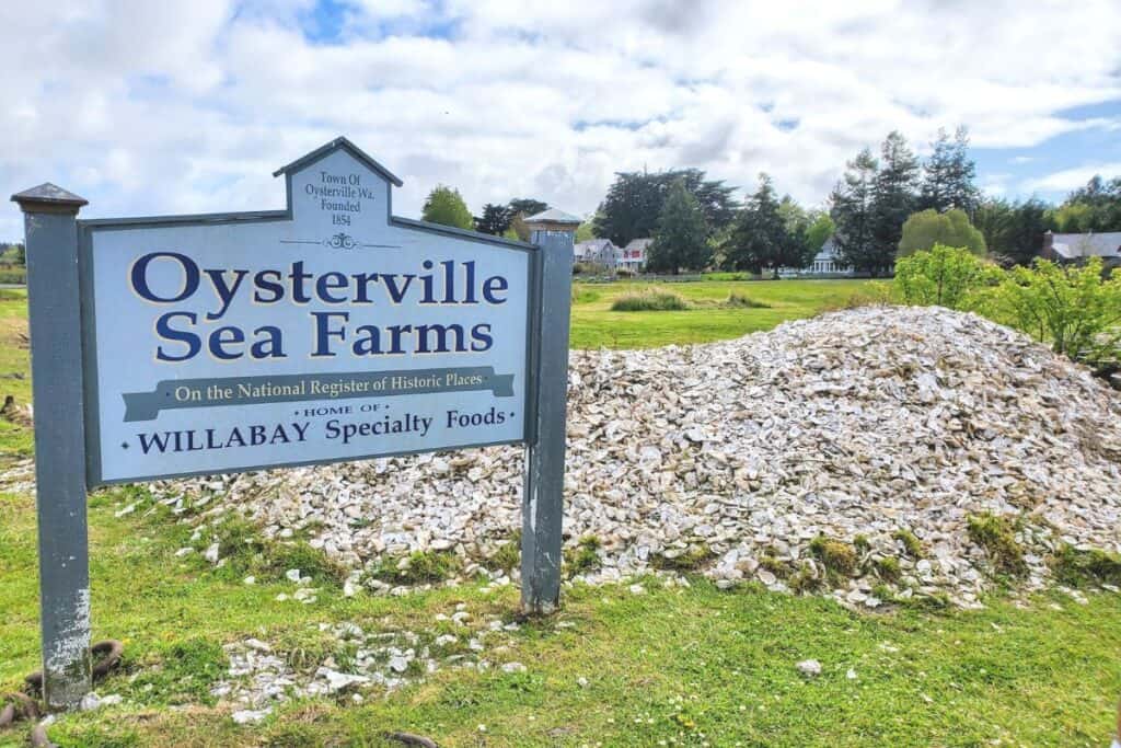 A mound of oyster shells and a sign for Historic Oysterville Sea Farms at Willapa Bay, Washington