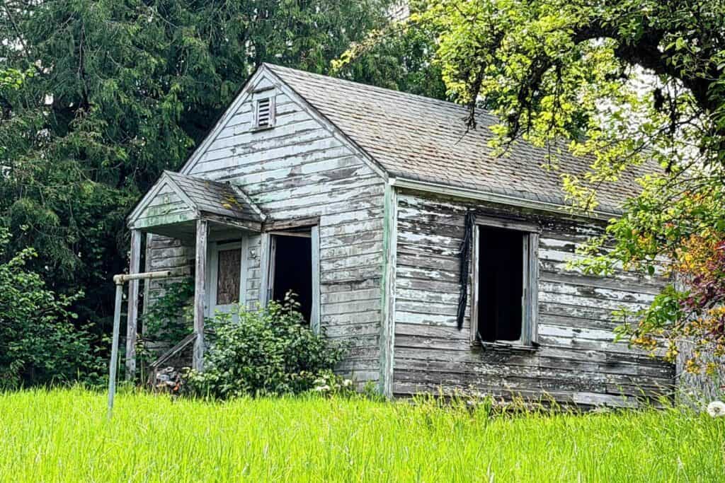Abandoned farmhouse along the road to Ocosta in Shelton, Washington Abandoned weathered farmhouse surrounded by grass and trees near Shelton, Washington.