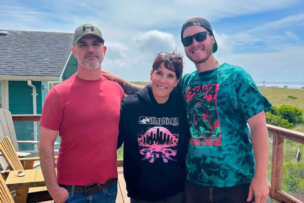 Family Trip Beach House Deck Moclips Washington A woman and two adult men smiling together on a sunny wooden deck of a beach house in Moclips WA.