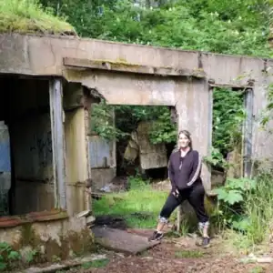 A woman standing in front of the broken concrete remains of Fort Canby in Cape Disappointment.