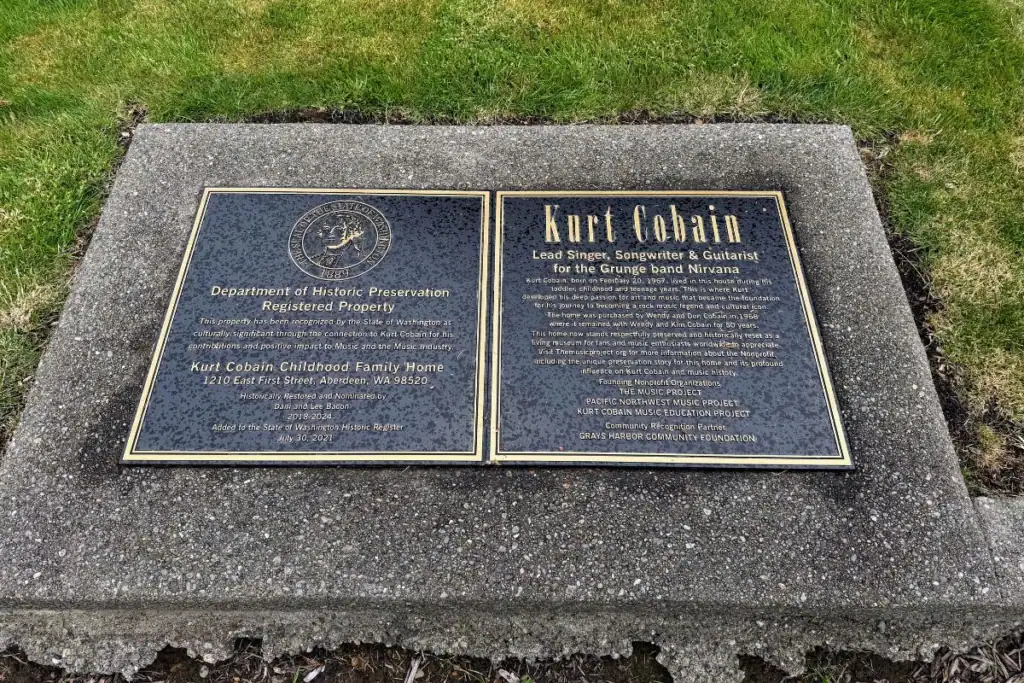 Kurt Cobain Childhood Family Home Historic Plaque The official Department of Historic Preservation bronze plaques on the ground marking the Kurt Cobain Childhood Family Home property at 1210 East First Street in Aberdeen Washington.