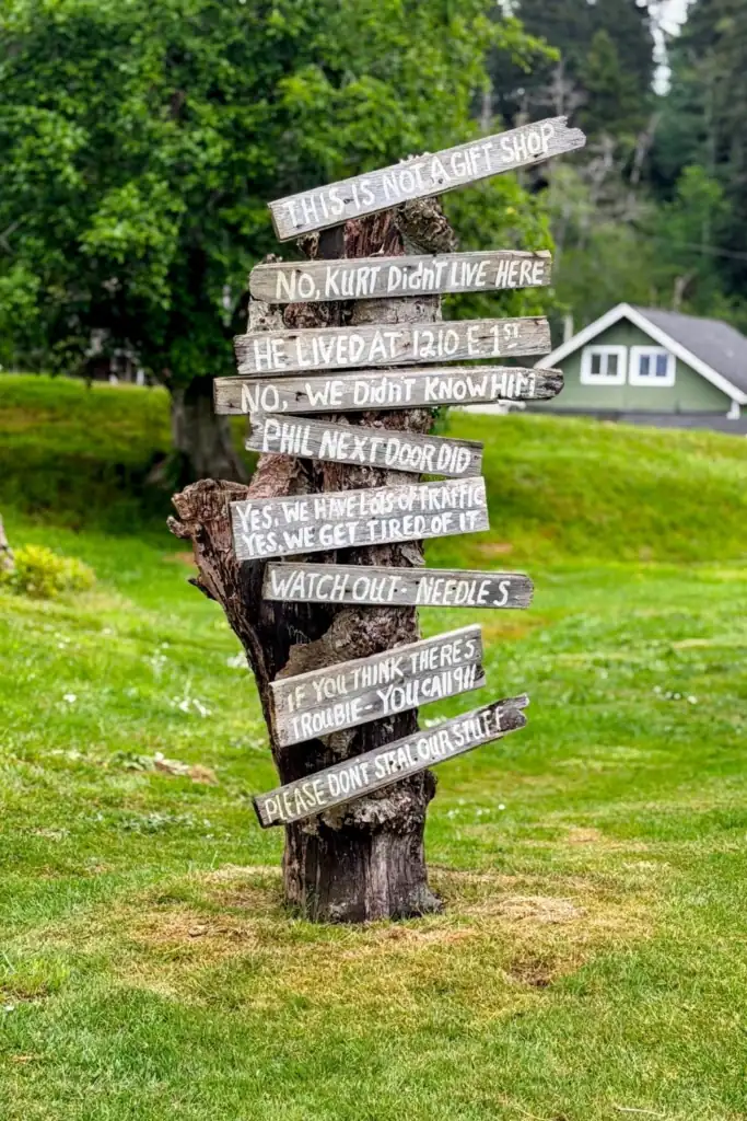 A rustic tree trunk with hand painted wooden signs from neighbors outside Kurt Cobain Memorial Park in Aberdeen WA.