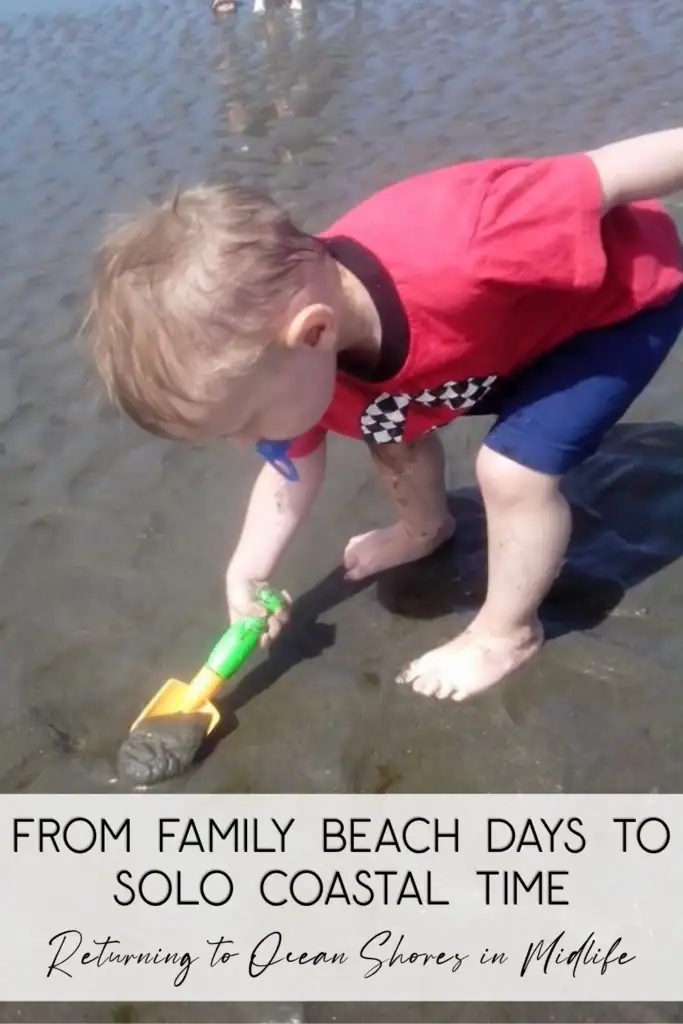 ocean-shores-wa-midlife-solo-travel-pinterest-pin A toddler in a red shirt and blue shorts playing with a green and yellow plastic shovel in the wet sand at Ocean Shores WA beach.