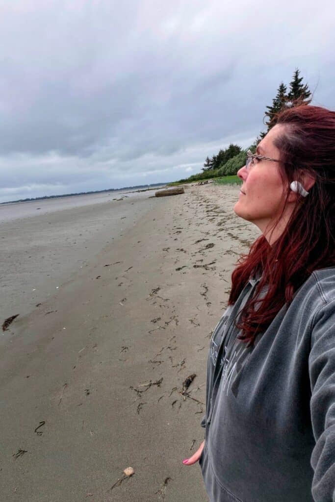 Walking the quiet shoreline at Ocosta-by-the-Sea in Washington Solo female traveler walking along the quiet beach at Ocosta-by-the-Sea near Westport, Washington under gray Pacific Northwest skies.