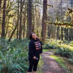 A woman standing on a trail in the Quinault Rainforest of Washington State.