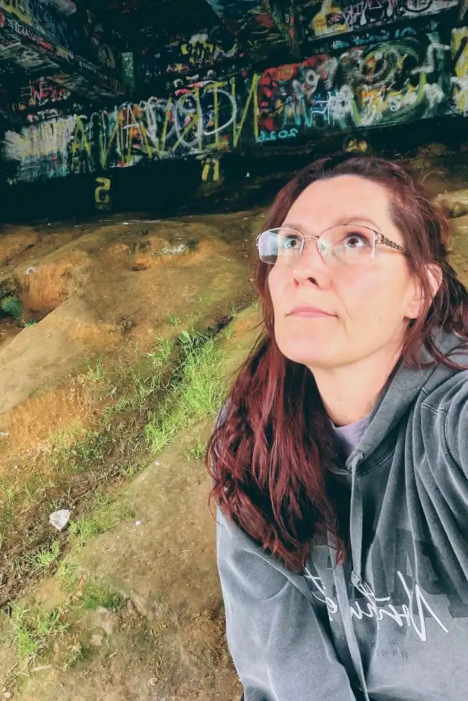 Reflecting Under the Young Street Bridge - PNWTravelGirl Travel blogger PNWTravelGirl sitting thoughtfully under the graffiti covered Young Street Bridge in Aberdeen Washington.