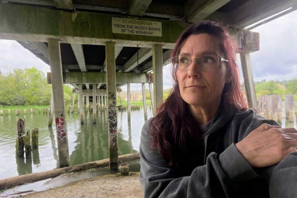 Reflecting beneath the bridge in Aberdeen Washington Thoughtful woman sitting beneath the Young Street Bridge over the murky Wishkah River at Kurt Cobain Memorial Park in Aberdeen, Washington.