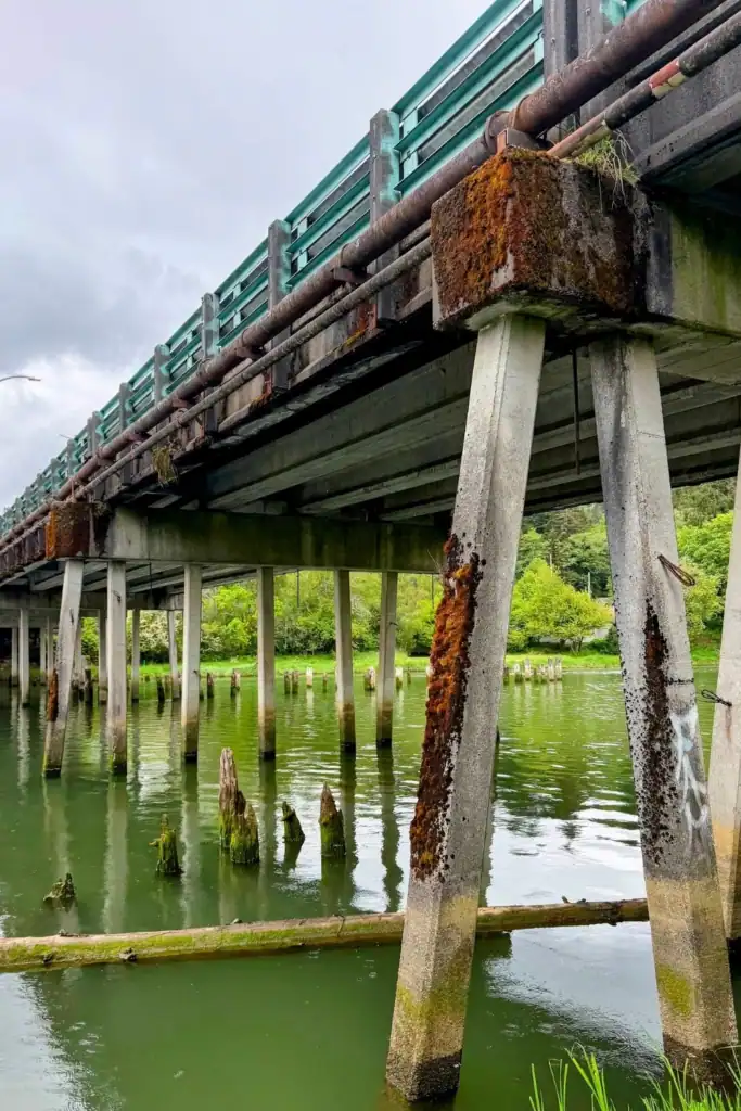 Young Street Bridge and Wishkah River in Aberdeen, WA The concrete pillars and old wooden pilings of the Young Street Bridge over the green Wishkah River in Aberdeen Washington.