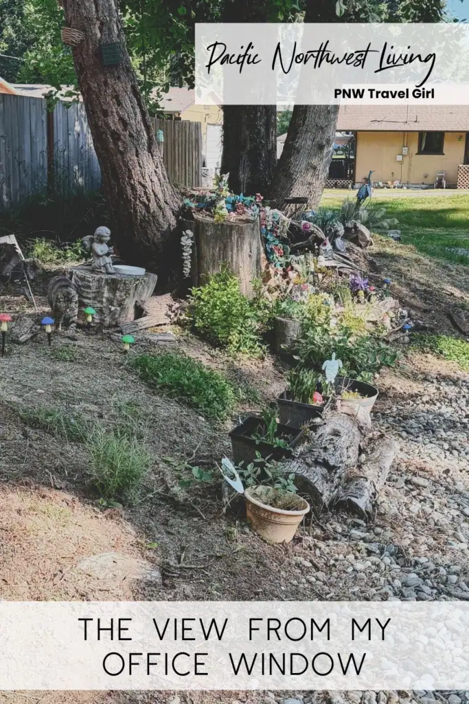 Front yard garden with trees, flowers, rocks, and small decorations in the Pacific Northwest. Text overlay reads “The View From My Office Window.”
