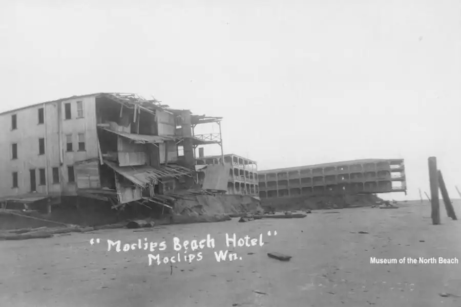 Historic photo of a storm-damaged building collapsing near the water on Moclips Beach in Washington.
