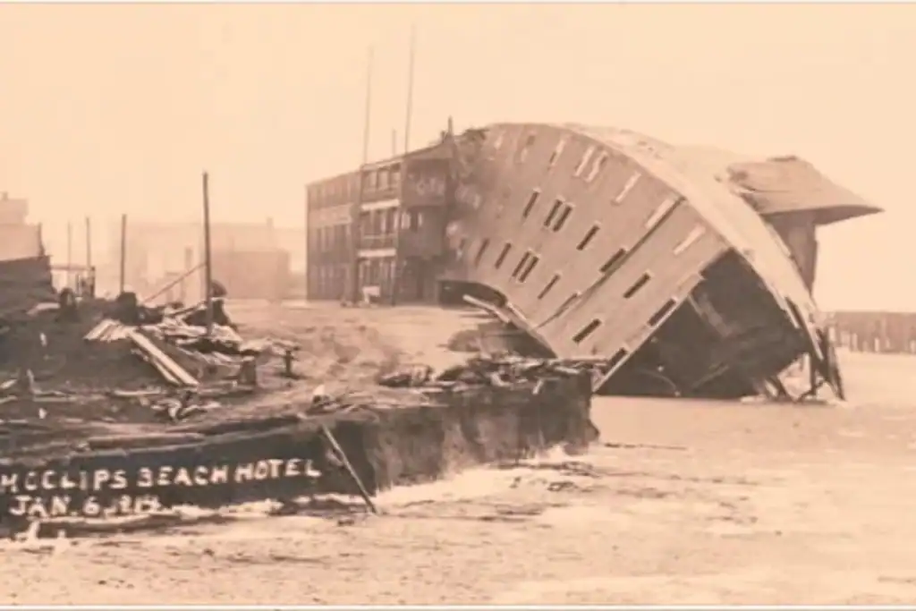 Historical postcard showing the collapse of the Moclips Beach Hotel during a severe Pacific storm in January 1913. Vintage black and white postcard showing the massive three-story Moclips Beach Hotel capsizing into the ocean dunes after a violent winter storm.
